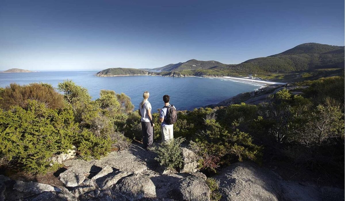 Hikers at a granite summit looking across bays and islands at Wilsons Promontory